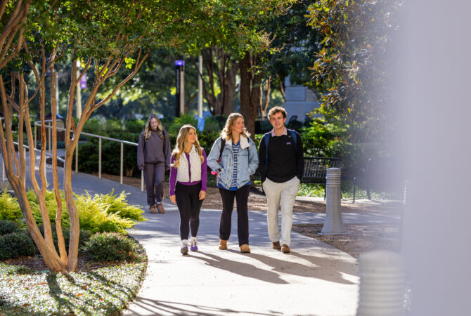 Three students talk while walking across the TCU campus, October 30, 2025. Photo by James Anger.